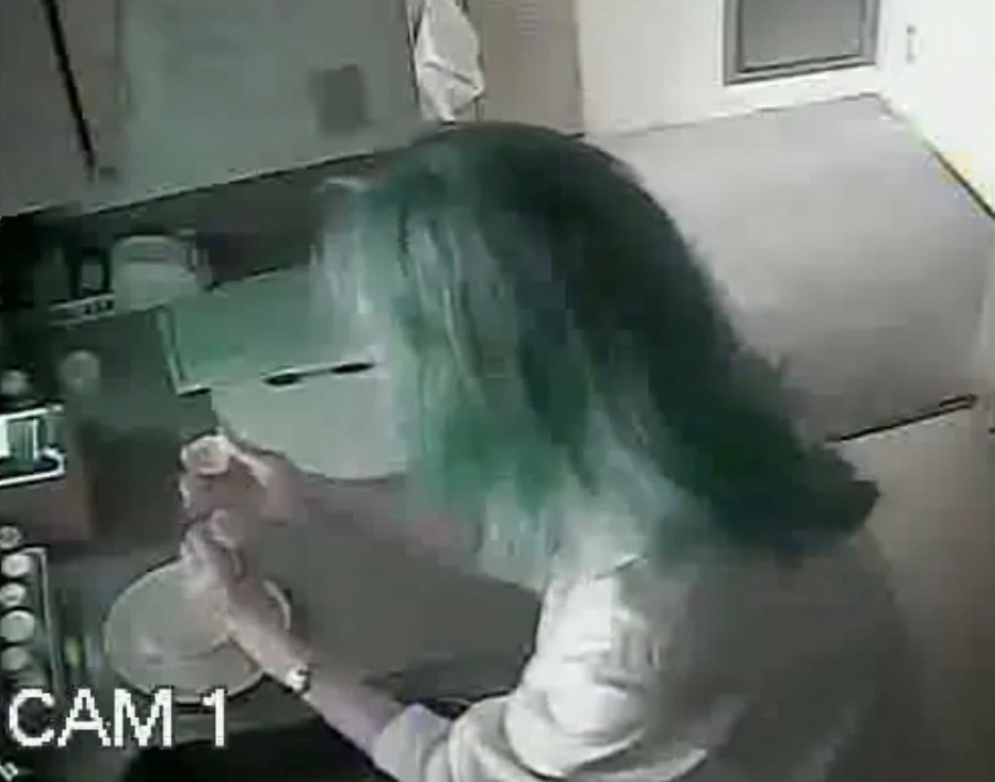 A screen grab from a hidden security camera of nurse taking pills from a bottle.