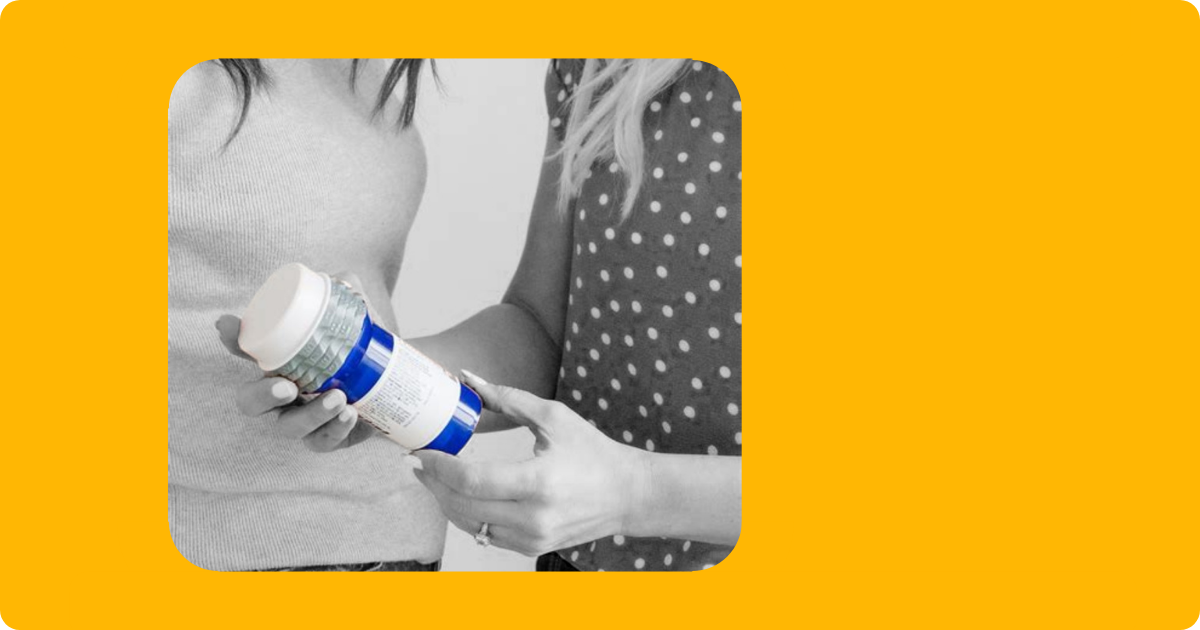 Two female presenting people examine a blue Safe-RX bottle.